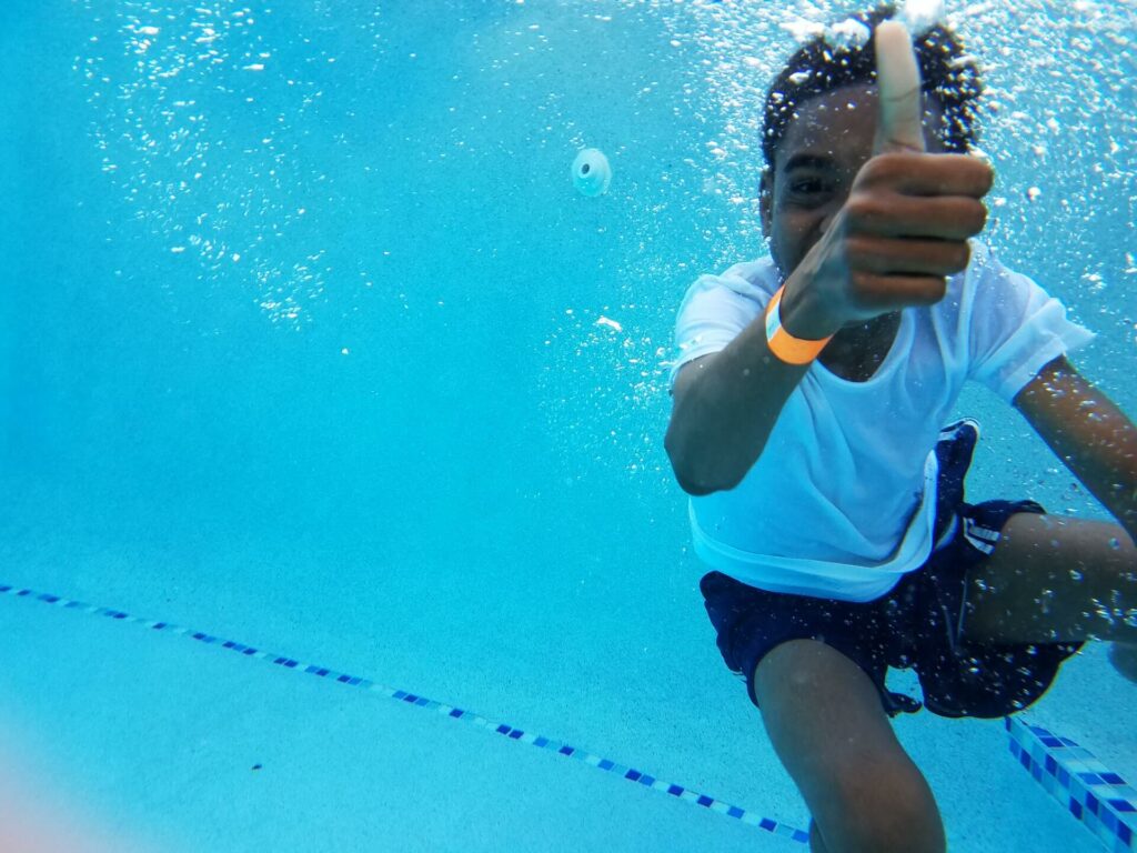 boy underwater giving a thumbs up because he's excited to register for swim classes